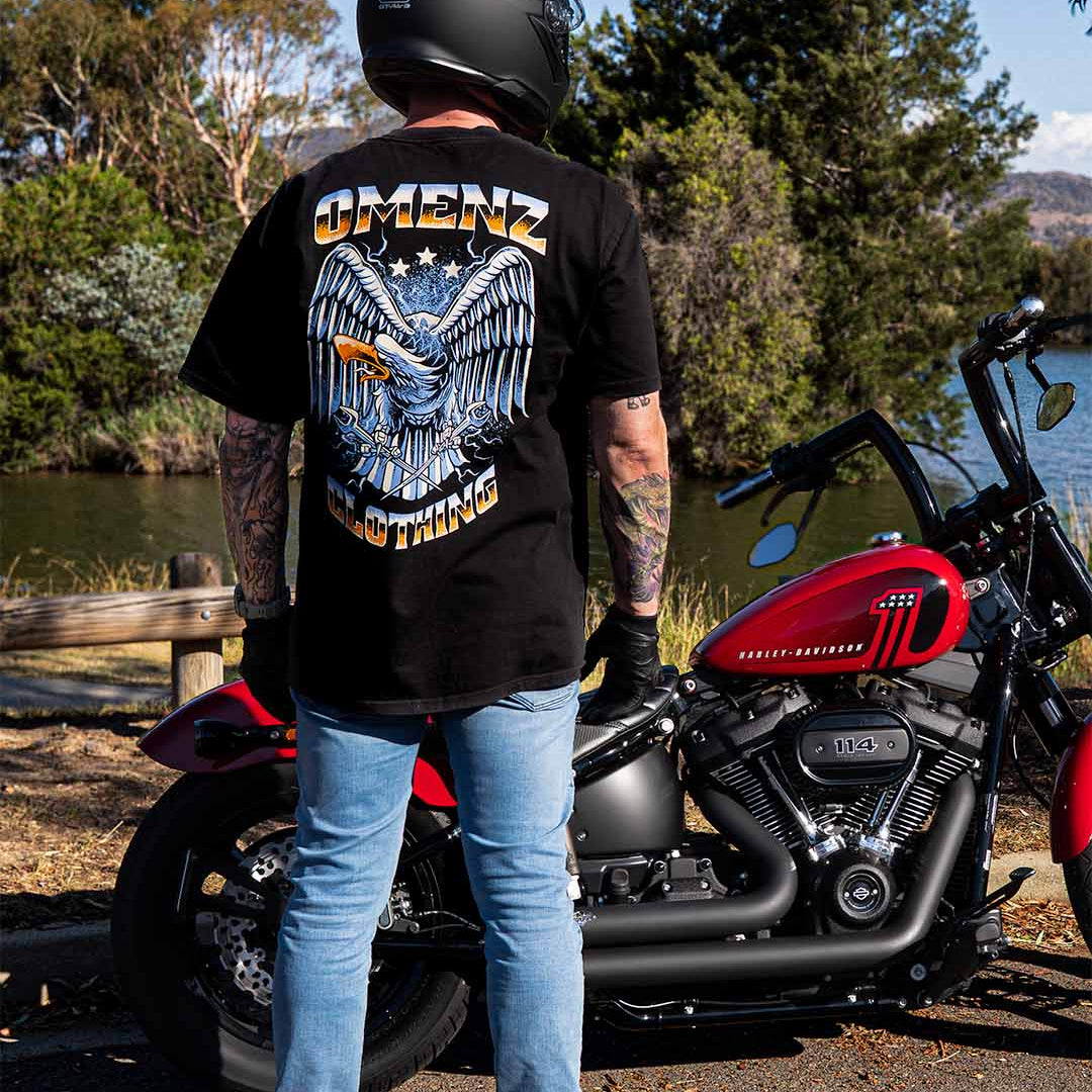 Man standing next to his Harley Davidson motorcycle wearing an Omenz Liberty unisex t-shirt