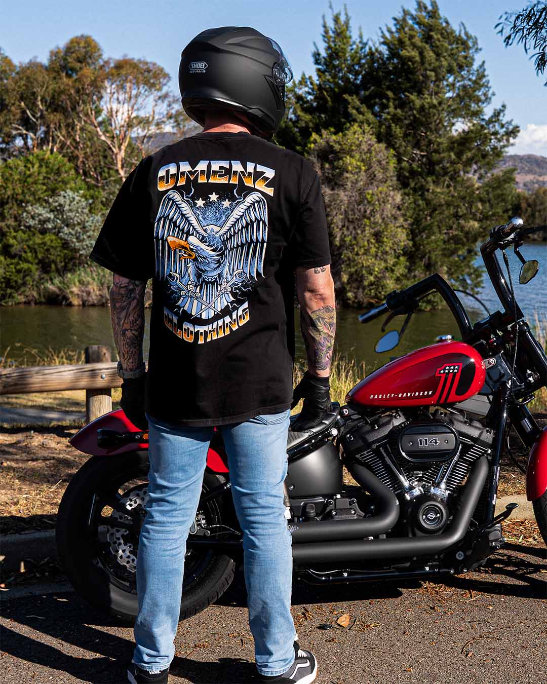 Man standing next to his Harley Davidson motorcycle wearing an Omenz Liberty unisex t-shirt