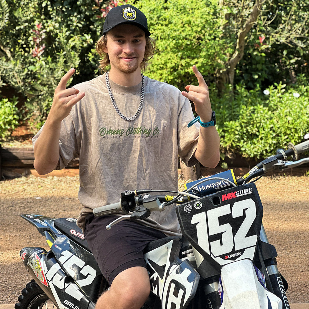 Person sitting on a dirt bike giving a thumbs-up gesture.